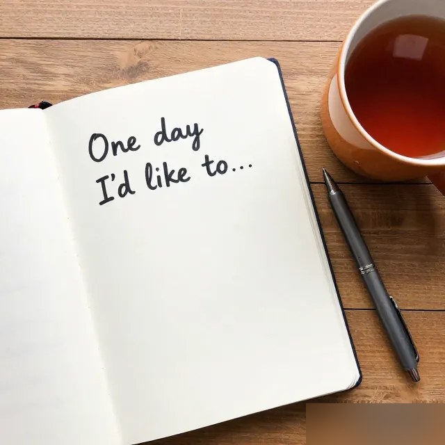 An open notebook with 'plan A / plan B' handwritten in two columns, next to a cup of tea and a folded umbrella.